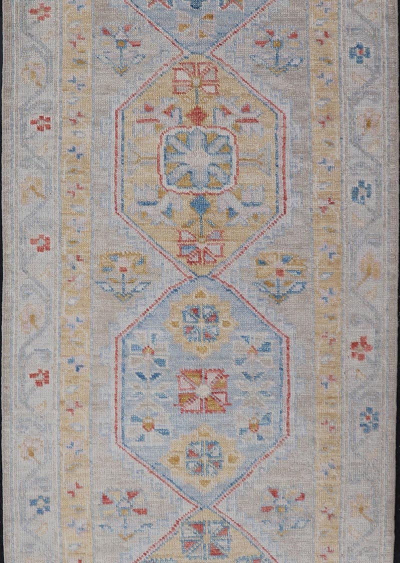 Hand - Knotted Floral Medallion Oushak Runner in Blue and Yellow This piece showcases brilliant medallions encasing star - like motifs in yellow, coral, orange, light blue, and cream. The border displays a yellow band between a cream background.... - Keivan Woven ArtsAWR - 6116 - 20013Rug