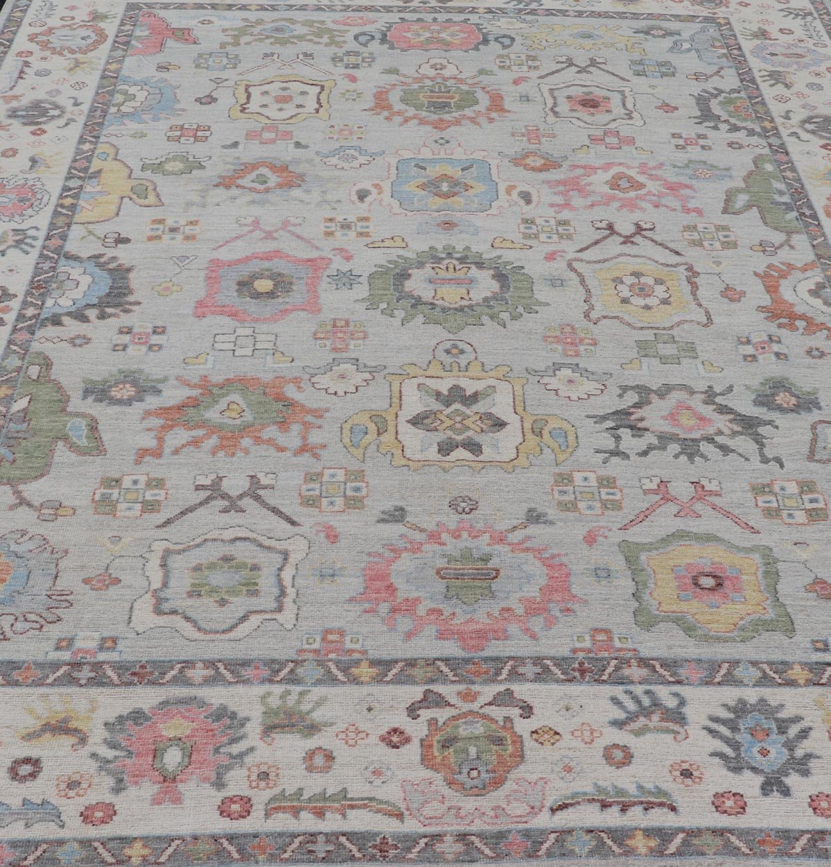 Oushak Floral Motif on Light Grey Background and Colorful Design The border and field are covered in floral - like motifs filled with colors such as pink, green, gold, teal and red - oranges on top of silvery grey background. The border showcases a ... - Keivan Woven ArtsAWR - 6148 - 20025Rug