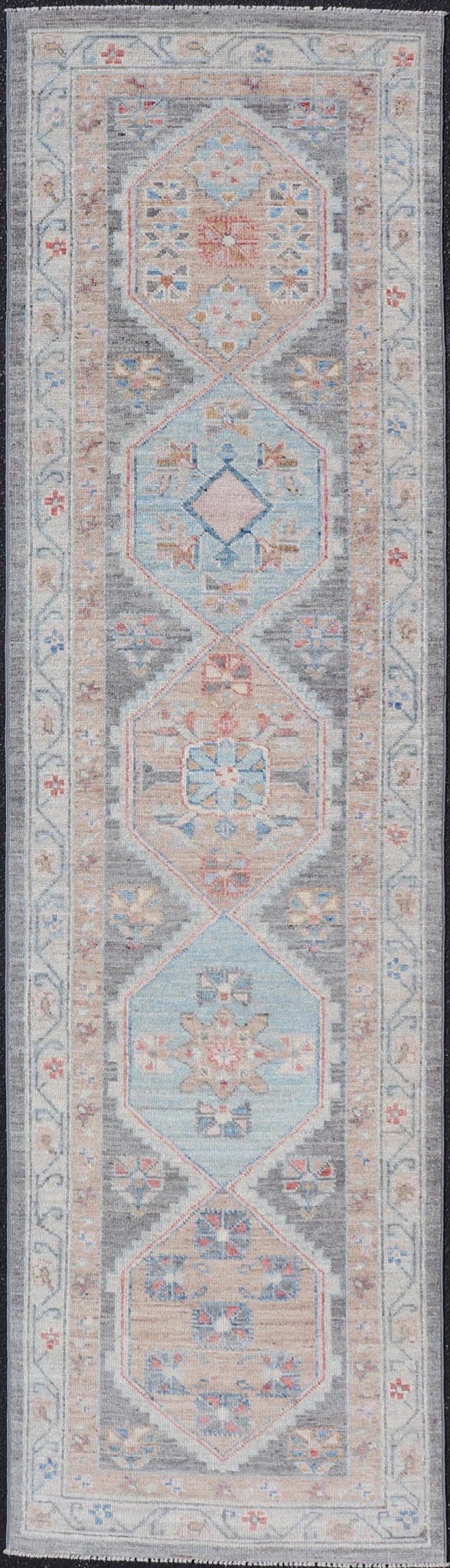 Floral Medallion Oushak Runner With Tribal Motifs and On A Gray Background This Hand - Knotted Afghan Oushak presents a double - lined floral border on top of a dark taupe background, accenting colors such as blue, red, and peach. The field disp... - Keivan Woven ArtsAWR - 6296 - 19905Rug
