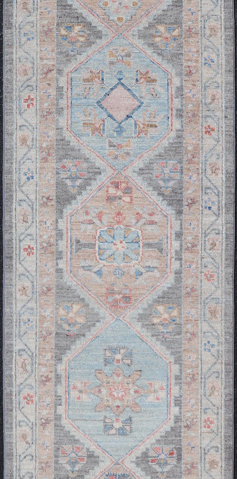 Floral Medallion Oushak Runner With Tribal Motifs and On A Gray Background This Hand - Knotted Afghan Oushak presents a double - lined floral border on top of a dark taupe background, accenting colors such as blue, red, and peach. The field disp... - Keivan Woven ArtsAWR - 6296 - 19905Rug
