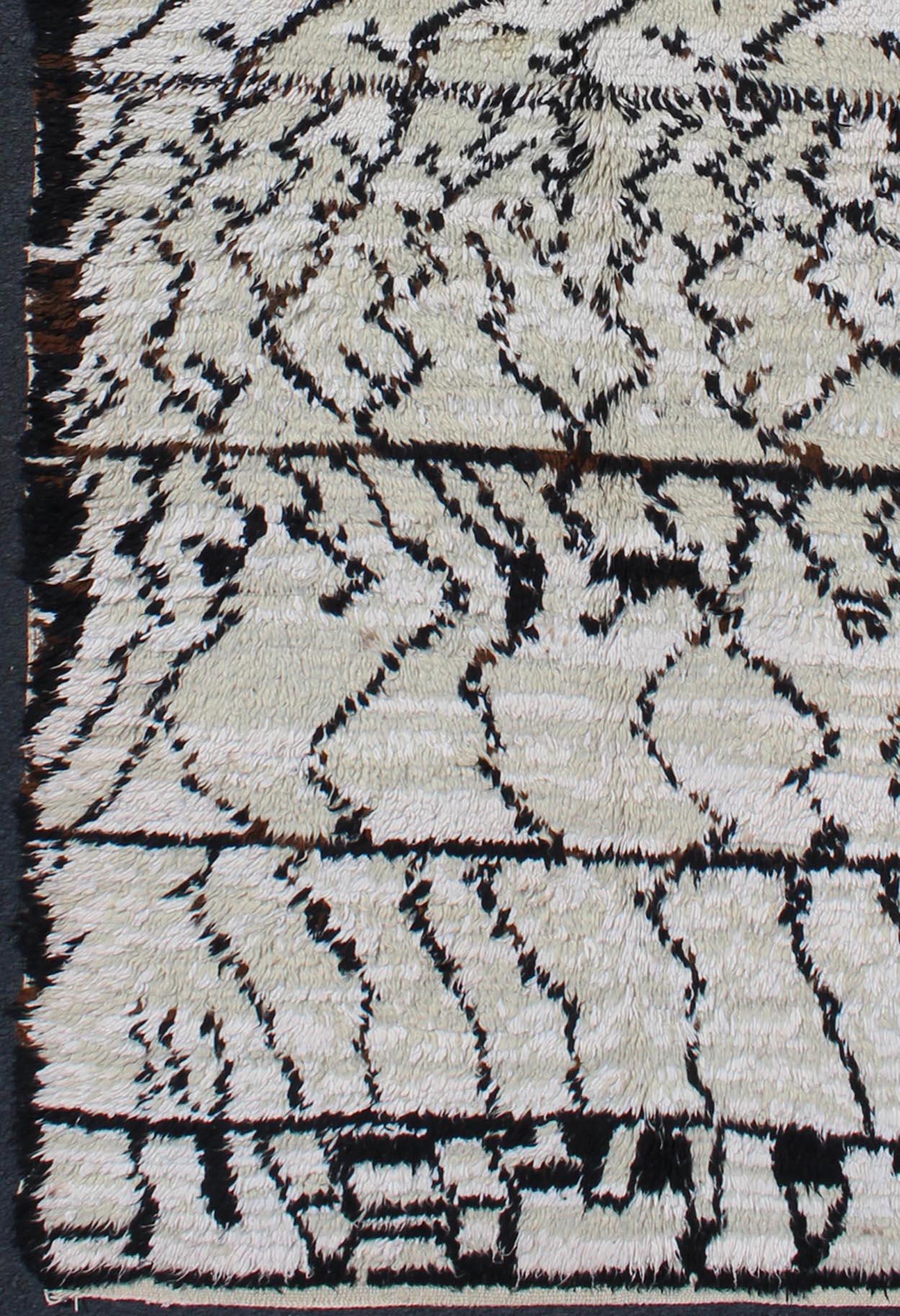 Vintage Moroccan Azilal Rug in White/Cream and Black for Modern Interiors This exquisite piece features a graphic handwoven Berber design with randomly drawn highlights, this piece is packed with motifs and symbols. The white or ivory colors are... - Keivan Woven ArtsBDS - 136622 - 7279Rug