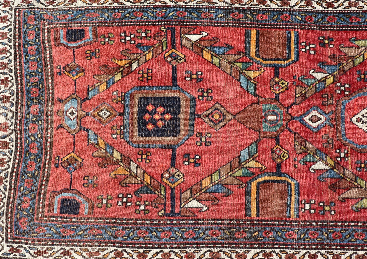Kurdish Antique Runner in Vibrant Red Background and Multi - tiered Border This early 20th century antique Kurdish runner features a triple - lined floral border, emboldening an ivory stripe between two blue edges. The field features a tribal, sub - g... - Keivan Woven ArtsEMB - 9523 - P13064 - 14668Rug