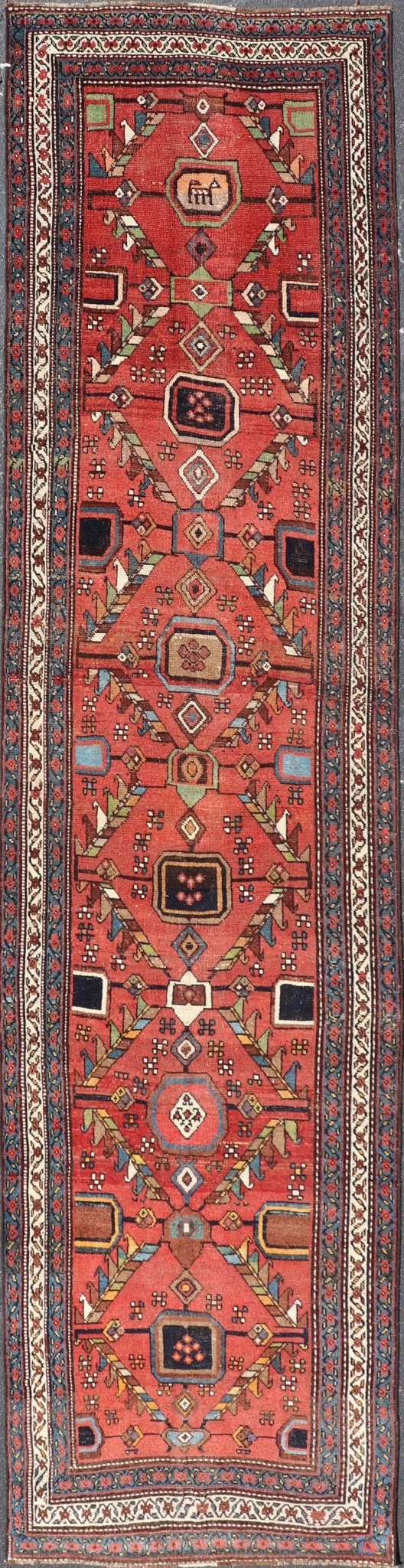 Kurdish Antique Runner in Vibrant Red Background and Multi - tiered Border This early 20th century antique Kurdish runner features a triple - lined floral border, emboldening an ivory stripe between two blue edges. The field features a tribal, sub - g... - Keivan Woven ArtsEMB - 9523 - P13064 - 14668Rug