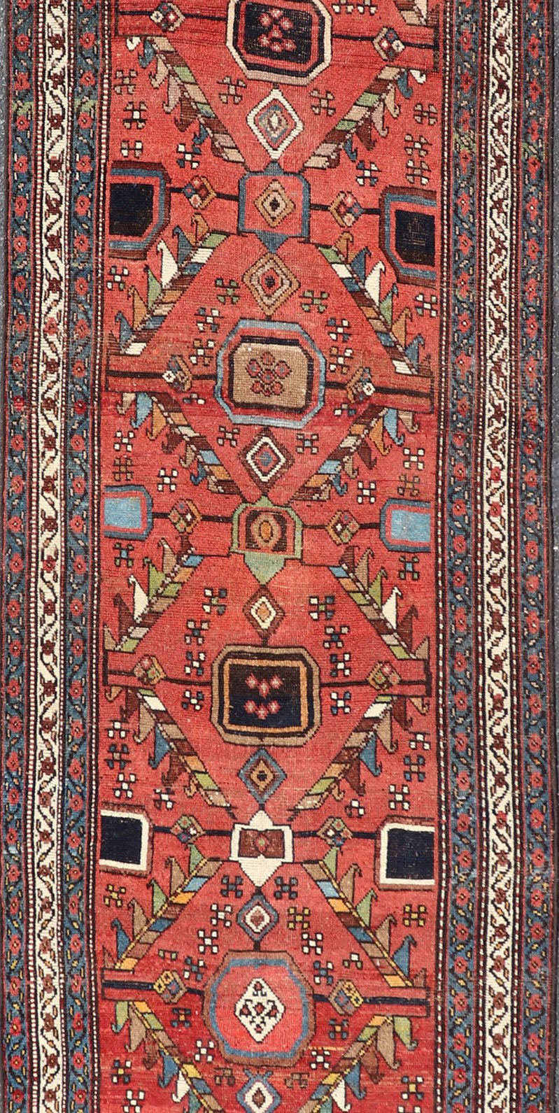 Kurdish Antique Runner in Vibrant Red Background and Multi - tiered Border This early 20th century antique Kurdish runner features a triple - lined floral border, emboldening an ivory stripe between two blue edges. The field features a tribal, sub - g... - Keivan Woven ArtsEMB - 9523 - P13064 - 14668Rug