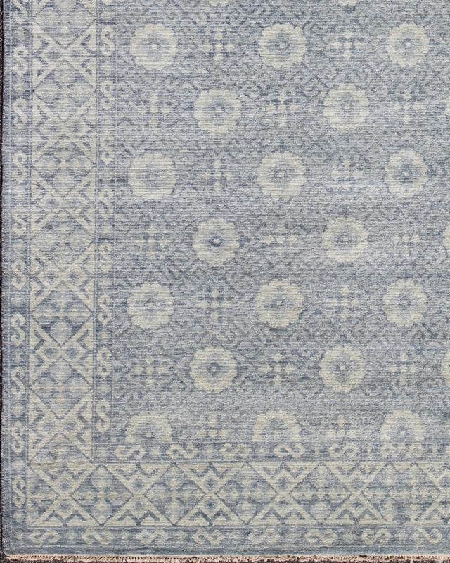 Vintage Khotan Rug in White and Blue. Measures: 9'2 x 12'1. This superb woolen Khotan hailing from India features an all over design with geometric shapes and patterning enclosed within a complementary border. The rug is rendered in shades of whi... - Keivan Woven ArtsIN - JAI - 5385 - 6967Rug