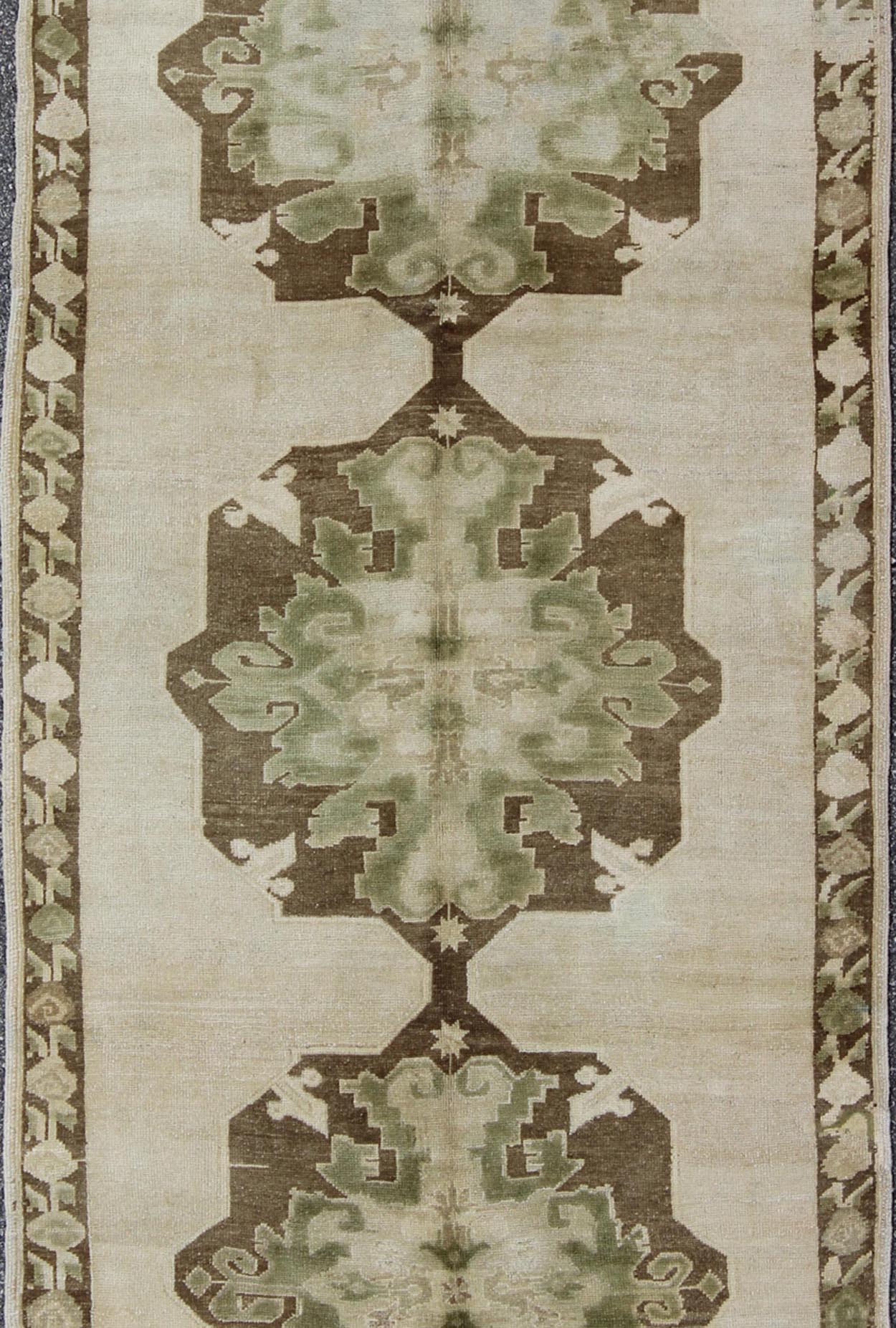 Green Turkish Oushak Runner This lovely Oushak runner displays three elegant medallions of multi - green colors on a solid cream field. The variety of green colors includes olive green, crocodile green and seaweed green. The minimal border coordin... - Keivan Woven ArtsTU - ISA - 3362 - 5740Rug