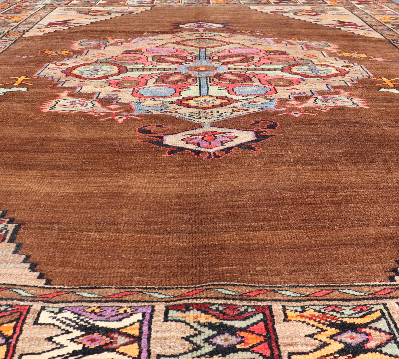 Vintage Turkish Kars Rug With Medallion On A Brown Field with Pops of Color. Keivan Woven Arts / rug/ TU - MTU - 3489, country of origin / type: Turkey / Oushak / Kars, circa 1940 Measures: 9'4 x 10'2. This Turkish Kars rug has been handwoven in Turk... - Keivan Woven ArtsTU - MTU - 3489 - 6853Rug
