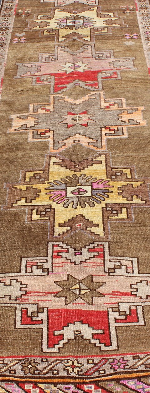 Unique & Colorful Turkish Kars Runner with Tribal Designs and Geometric Motifs Vintage Turkish runner in greenish Brown background, ivory border with accent colors, red, pink, tan, green, bright yellow, taupe, rug/TU - UGU - 4806, country of origin... - Keivan Woven ArtsTU - UGU - 4806 - 10287Rug