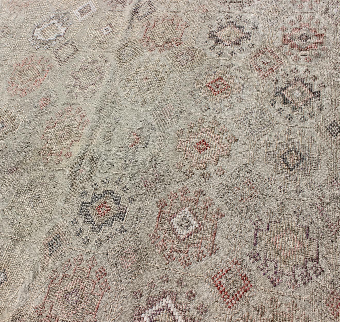 Vintage Turkish Kilim Featuring Muted Colors and All-Over Tribal Motif Design
 
 
 
 Measures 4'7 x 8'0 
 
 This rug features an asymmetrical design of tribal crests decorating the light blue-grey field. The crests are rendered in varying muted shades ...