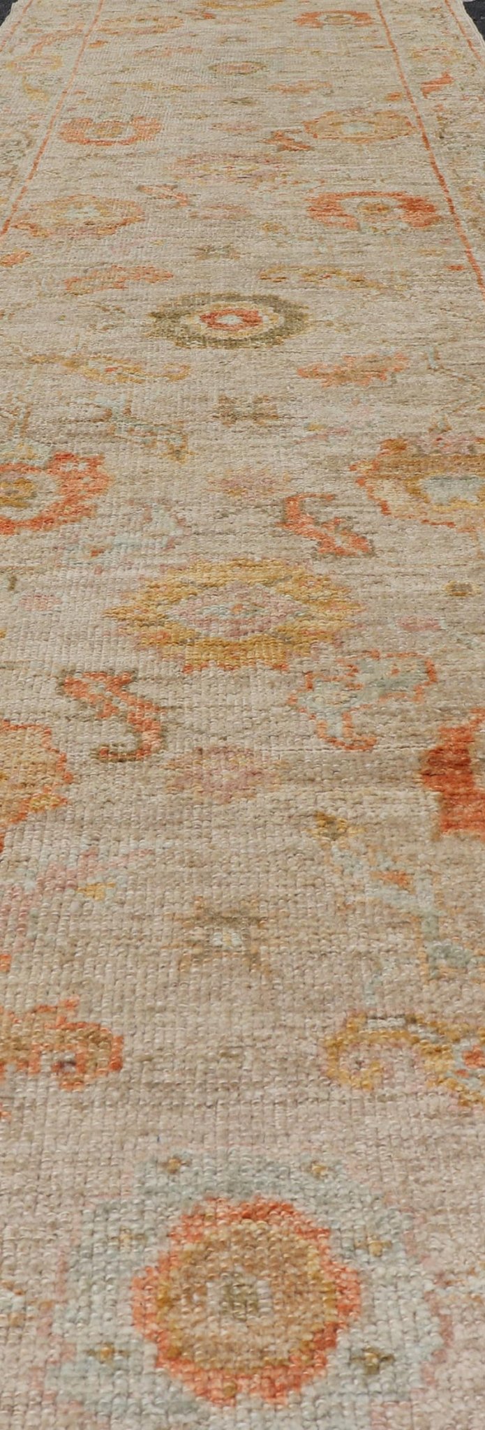 Angora Turkish Oushak Floral Runner in Cream with Pops of Orange, Green and Blue This angora Oushak is unique with is creamy background, to the floral like design rendered in coral, tangerine, forest green, salmon, and hints of sky blue. The bor... - Keivan Woven ArtsAN - 149531 - 19947Rug