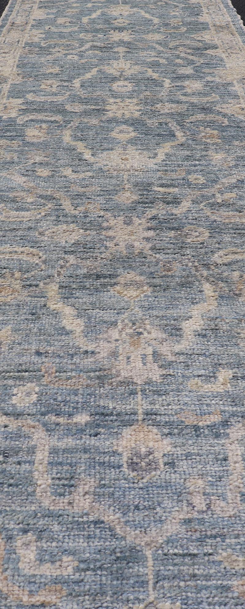 Angora Turkish Oushak Runner with Floral Design and Medium Blue and Gray Border This Oushak Runner is rendered in a medium blue background and a light gray border. The design is an arabesque - like floral pattern, cased within a banded sub - floral ... - Keivan Woven ArtsAN - 149801 - 19935Rug