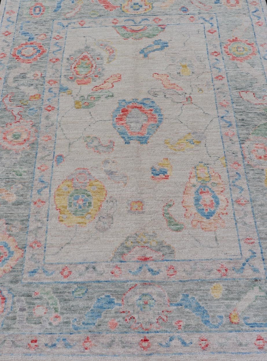 Modern All - Over Floral Oushak with Muted Background and Accent Colors Modern Oushak featuring an all - over, arabesque - like floral design, rendered in saturated oceanic blue, gold, green, red, and red - orange. The background is rendered in a co... - Keivan Woven ArtsAWR - 356 - 19959Rug