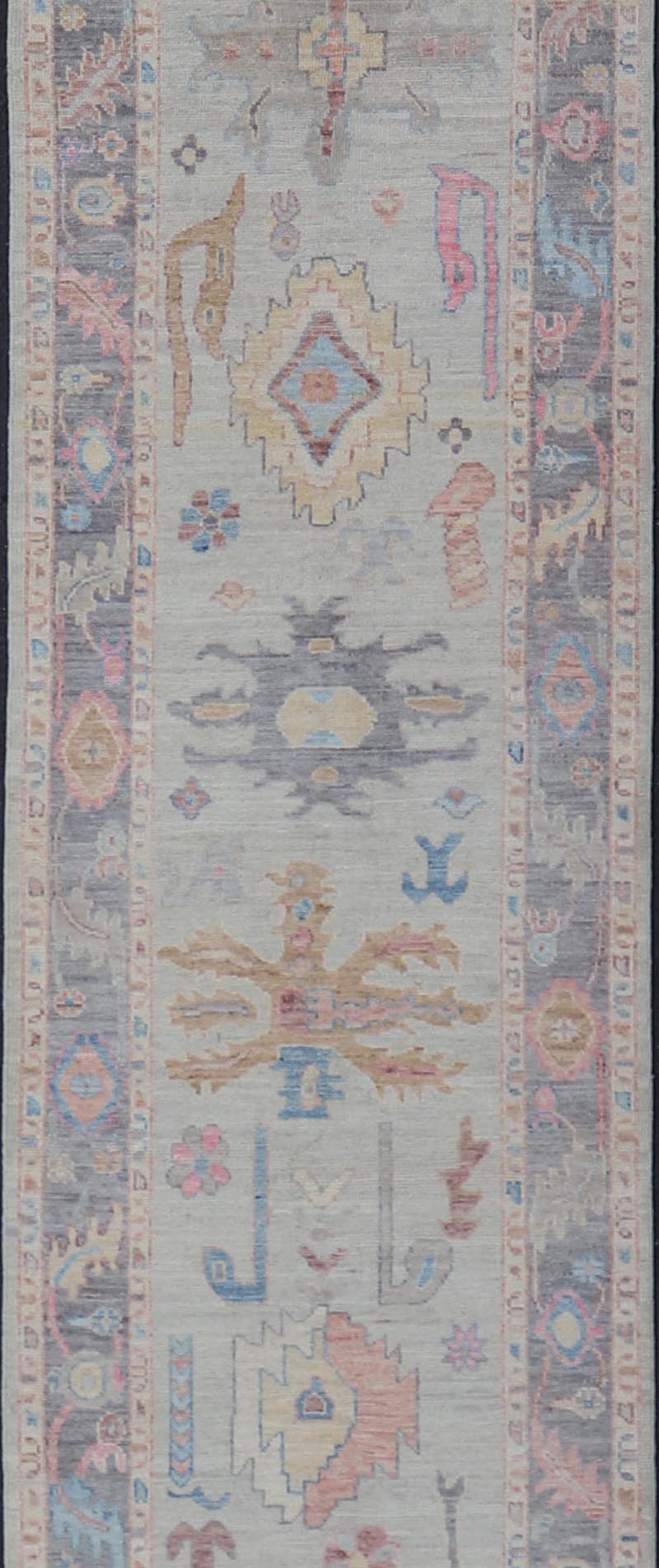 Hand - Knotted Modern Tribal Oushak Long Runner in Wool with Colorful Motifs This long Oushak runner has a cream background with a light gray border. The border has a leaflet - like design is rendered in green, coral, and blue with a hint of ye... - Keivan Woven ArtsAWR - 6026 - 19965Rug