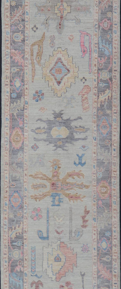 Hand - Knotted Modern Tribal Oushak Long Runner in Wool with Colorful Motifs This long Oushak runner has a cream background with a light gray border. The border has a leaflet - like design is rendered in green, coral, and blue with a hint of ye... - Keivan Woven ArtsAWR - 6026 - 19965Rug