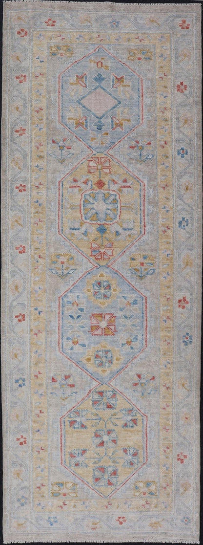 Hand - Knotted Floral Medallion Oushak Runner in Blue and Yellow This piece showcases brilliant medallions encasing star - like motifs in yellow, coral, orange, light blue, and cream. The border displays a yellow band between a cream background.... - Keivan Woven ArtsAWR - 6116 - 20013Rug
