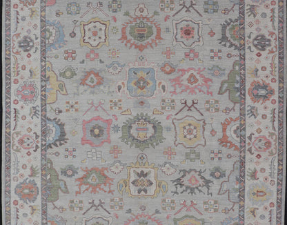 Oushak Floral Motif on Light Grey Background and Colorful Design The border and field are covered in floral - like motifs filled with colors such as pink, green, gold, teal and red - oranges on top of silvery grey background. The border showcases a ... - Keivan Woven ArtsAWR - 6148 - 20025Rug