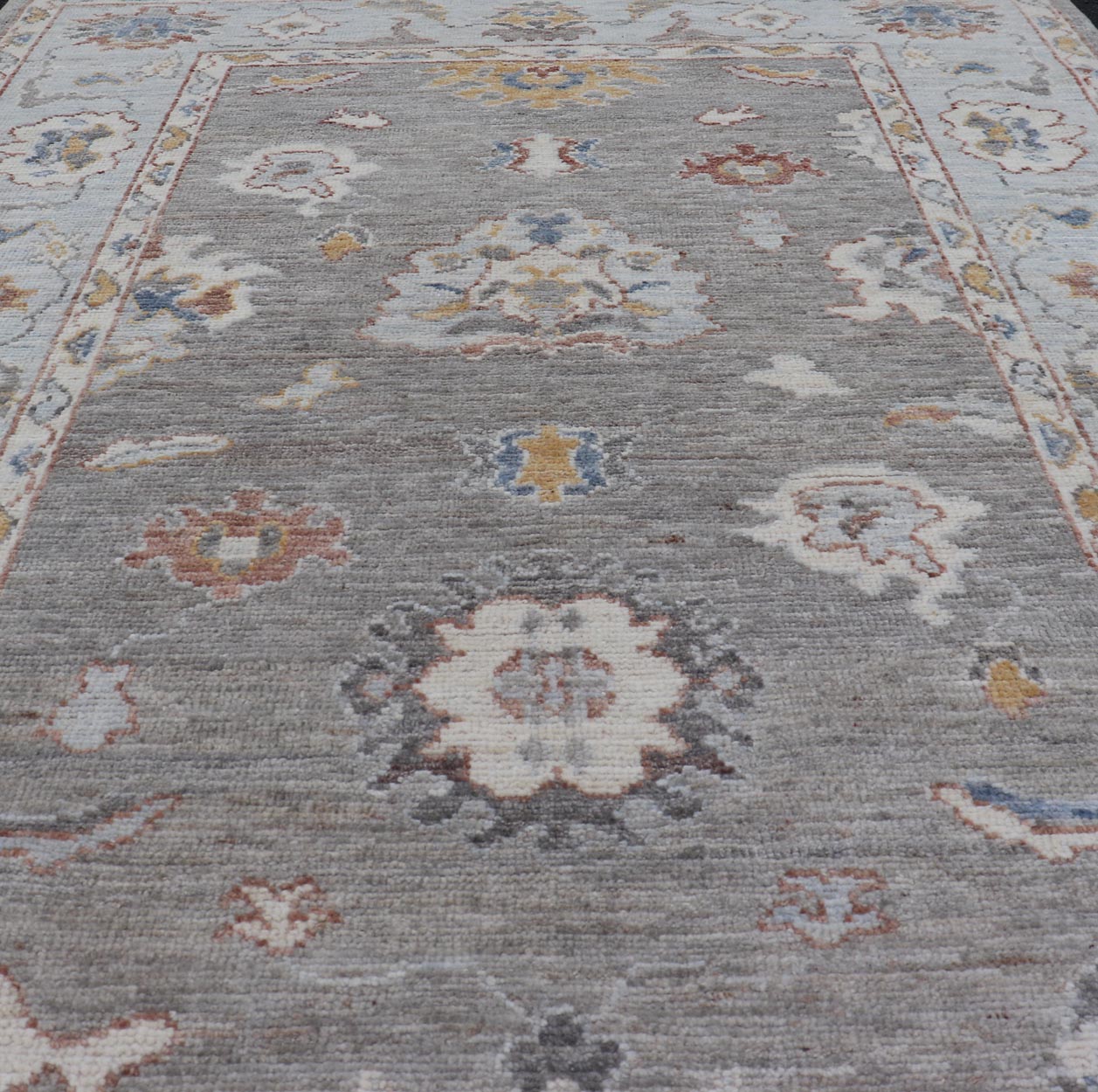 Modern Hand Knotted Oushak with Muted Background and Earthy Accents This beautiful rug starts in a light gray background, paired with a steel blue in the border. The design is an all - over Oushak floral design, highlighting unique colors, su... - Keivan Woven ArtsAWR - 6320 - 20055Rug