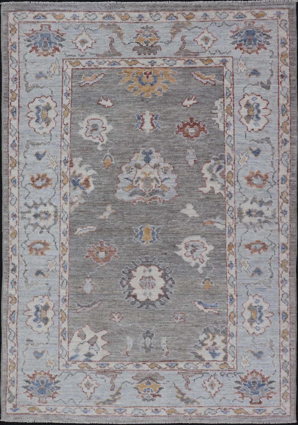 Modern Hand Knotted Oushak with Muted Background and Earthy Accents This beautiful rug starts in a light gray background, paired with a steel blue in the border. The design is an all - over Oushak floral design, highlighting unique colors, su... - Keivan Woven ArtsAWR - 6320 - 20055