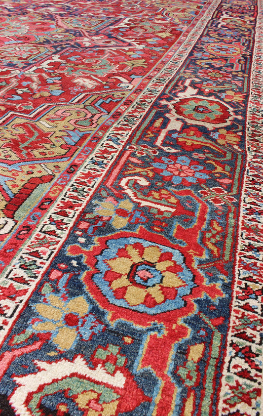 Antique Heriz Carpet with Stylized Floral Motifs and Complementary Border This magnificent antique Persian Heriz carpet from the early 20th century bears an exquisite design rendered in gorgeous, warm hues of red and various shades of blue. A hi... - Keivan Woven ArtsCA - 14882 - 517Rug