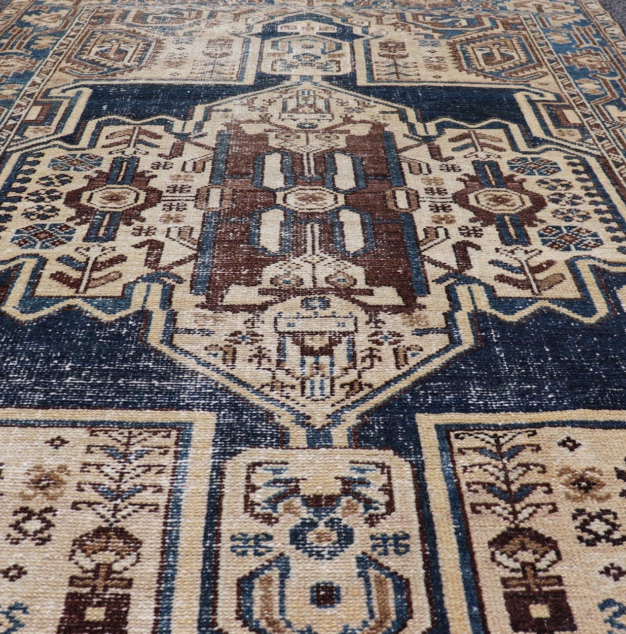 Measures: 4'4 x 6'9 The rug's central field showcases a prominent medallion pattern set against a deep blue background, accented with beige and brown geometric and floral motifs. The medallion itself is highly detailed, featuring a complex arrangem... - Keivan Woven ArtsEMB - 22237 - 22466