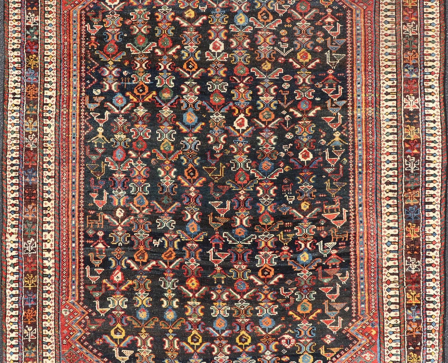 Measures: 5'7 x 8'10 This Qashgai rug has rich heritage and intricate design characteristic of this nomadic tribe from southwestern Iran. The rug features a dense, dark blue field adorned with a myriad of vibrant, detailed motifs, including ani... - Keivan Woven ArtsEMB - 22245 - 22508