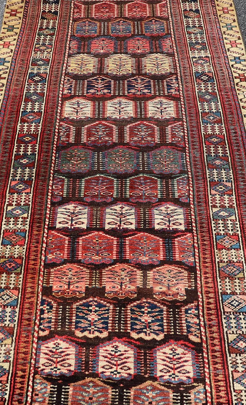 Measures: 3'3 x 8'4 This stunning antique Persian Kurdish runner showcases a vibrant and intricate design, reflecting the rich tribal heritage of Kurdish craftsmanship. The rug features a series of repeated medallions, each intricately detailed wit... - Keivan Woven ArtsEMB - 22288 - 26124Rug