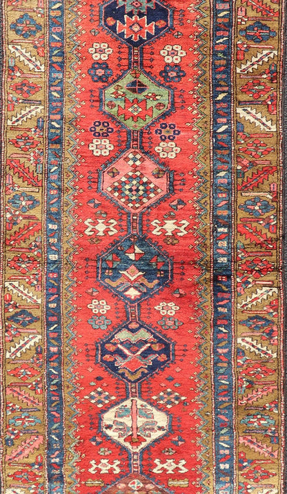 Antique Persian Heriz Runner in Reds, Blues, Pink, Ivory and Earthy Tones This gorgeous antique Persian Heriz runner features a red background imbued with ornate medallions running along the piece. Sub - geometric designs decorate the field, and a... - Keivan Woven ArtsEMB - 9577 - P13510 - 15128Rug