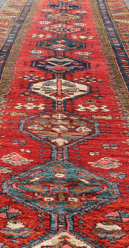 Antique Persian Heriz Runner in Reds, Blues, Pink, Ivory and Earthy Tones This gorgeous antique Persian Heriz runner features a red background imbued with ornate medallions running along the piece. Sub - geometric designs decorate the field, and a... - Keivan Woven ArtsEMB - 9577 - P13510 - 15128Rug