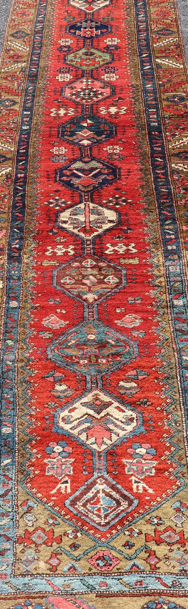 Antique Persian Heriz Runner in Reds, Blues, Pink, Ivory and Earthy Tones This gorgeous antique Persian Heriz runner features a red background imbued with ornate medallions running along the piece. Sub - geometric designs decorate the field, and a... - Keivan Woven ArtsEMB - 9577 - P13510 - 15128Rug