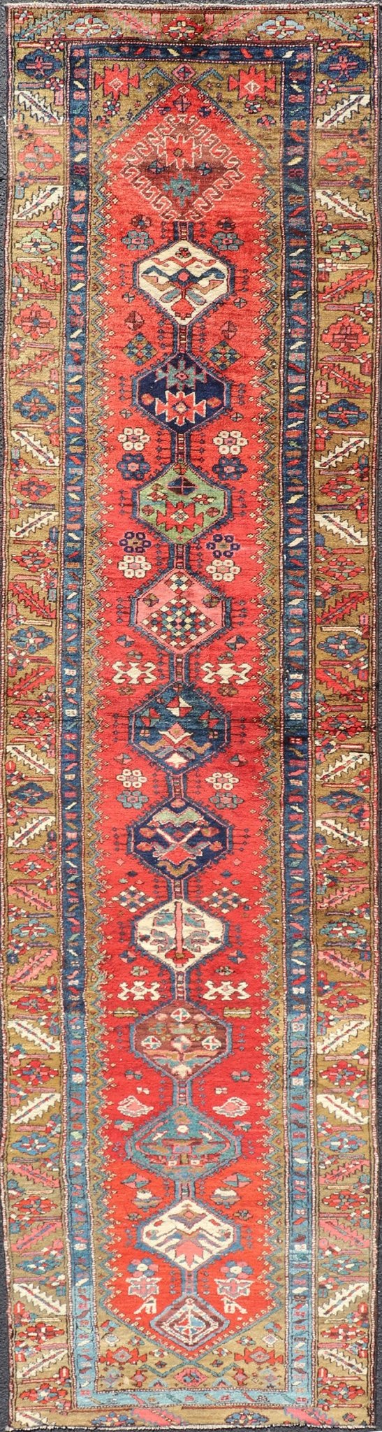 Antique Persian Heriz Runner in Reds, Blues, Pink, Ivory and Earthy Tones This gorgeous antique Persian Heriz runner features a red background imbued with ornate medallions running along the piece. Sub - geometric designs decorate the field, and a... - Keivan Woven ArtsEMB - 9577 - P13510 - 15128Rug