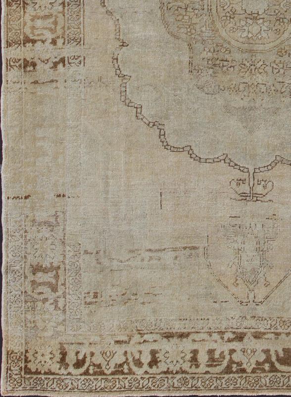 Antique Oushak Carpet in Taupe, Brown, Light Celadon Green and Neutral Colors Measures: 8'0'' x 12'1''. This antique Oushak wool rug features an over - sized medallion with detailed vines and flowers. A framework of floral motifs and styliz... - Keivan Woven ArtsEN - 141449 - 7203Rug