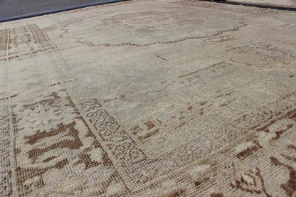Antique Oushak Carpet in Taupe, Brown, Light Celadon Green and Neutral Colors Measures: 8'0'' x 12'1''. This antique Oushak wool rug features an over - sized medallion with detailed vines and flowers. A framework of floral motifs and styliz... - Keivan Woven ArtsEN - 141449 - 7203Rug