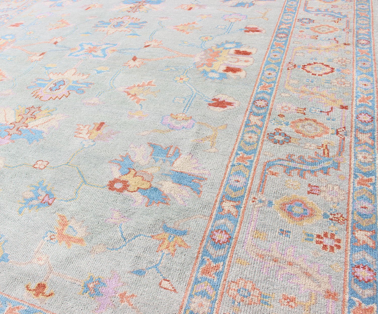 Hand - Knotted Floral Oushak Designed Rug in Light Blue, Orange, and Blue Measures 9'1 x 11'8 This wool Oushak was hand - knotted in the 2020's. The field and border both have a cool blue gray. The field and border also share floral and leaf... - Keivan Woven ArtsIN - CLR - 1002 - 13444