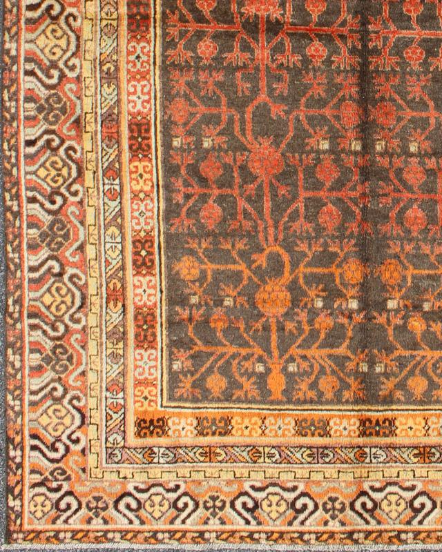 Antique Khotan Rug An antique, early 20th century, Central Asian Khotan rug with traditional all - over pomegranate pattern on a charcoal field surrounded by multiple complementary floral borders of gold and orange. Measures: 5'7 x 8'11. - Keivan Woven ArtsMP - 1610 - 157652 - 7881Rug