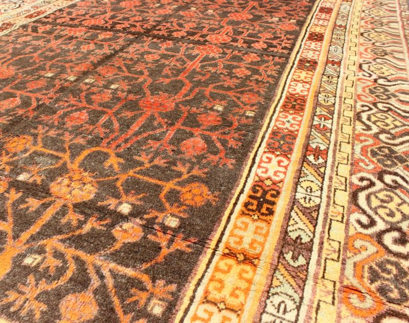Antique Khotan Rug An antique, early 20th century, Central Asian Khotan rug with traditional all - over pomegranate pattern on a charcoal field surrounded by multiple complementary floral borders of gold and orange. Measures: 5'7 x 8'11. - Keivan Woven ArtsMP - 1610 - 157652 - 7881Rug