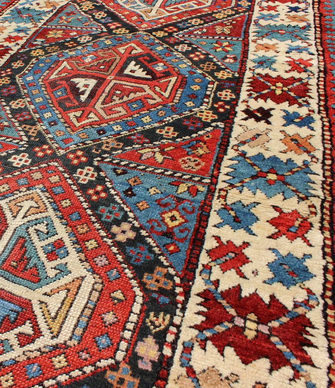 Antique Caucasian Kuba Rug This piece is an impeccable late 19th century Kuba rug with an indigo blue field beneath a geometric vinery trellis featuring bold polychrome medallions and stylized leaves. The ivory frame features repeating turtle mo... - Keivan Woven ArtsN15 - 0308 - 18Rug