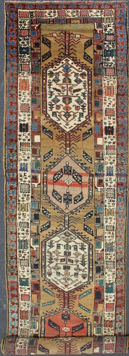 Long Tribal Persian Serab Runner The camel field in this piece is decorated with ivory strap work, navy blue lattice work and stylized Boteh and floral elements. A beautifully drawn Reciprocal Trefoil guard border is complemented by an ivory min... - Keivan Woven ArtsN15 - 0501 - 7695Rug