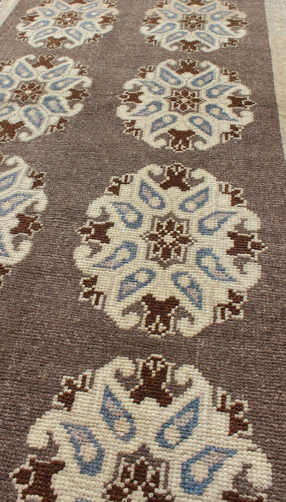 Tribal Turkish Oushak Carpet with Floral Medallions in Taupe, Ivory and Blue Measures: 2'9'' x 6'4''. This Turkish Oushak gallery rug features ten floral medallions that take center stage on a brown field. The border reveals tribal inspiratio... - Keivan Woven ArtsTU - ALK - 3562 - 6787Rug
