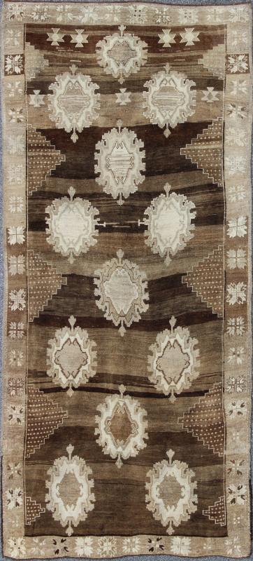 Large Gallery Oushak Rug with Geometric Design and Florals This gallery rug displays 12 medallions that take center stage on a mocha and chocolate brown field. The border reveals tribal inspiration in soft shades of taupe, ivory and chocolate br... - Keivan Woven ArtsTU - ALK - 3579 - 6810Rug