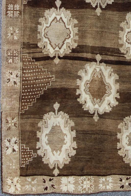 Large Gallery Oushak Rug with Geometric Design and Florals This gallery rug displays 12 medallions that take center stage on a mocha and chocolate brown field. The border reveals tribal inspiration in soft shades of taupe, ivory and chocolate br... - Keivan Woven ArtsTU - ALK - 3579 - 6810Rug