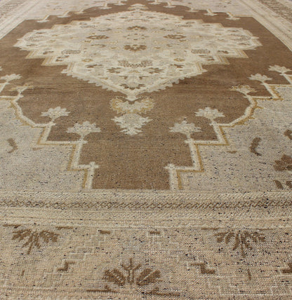 Vintage Turkish Oushak Rug in Brown Background and Neutral Colors Measures: 7'4 x 11'4 This lovely Turkish Oushak from the 1940's features a central medallion, which rests on a dark brown background, is surrounded by a light brown bor... - Keivan Woven ArtsTU - DUR - 506 - 3502Rug