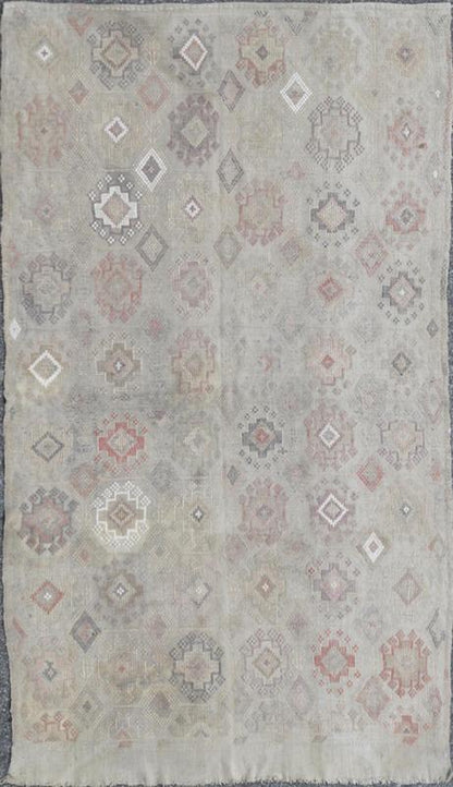 Vintage Turkish Kilim Featuring Muted Colors and All - Over Tribal Motif Design Measures 4'7 x 8'0 This rug features an asymmetrical design of tribal crests decorating the light blue - grey field. The crests are rendered in varying muted shades ... - Keivan Woven ArtsTU - NED - 136032 - 4618Rug