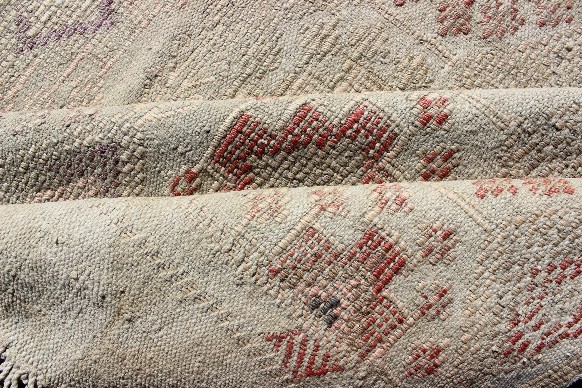 Vintage Turkish Kilim Featuring Muted Colors and All - Over Tribal Motif Design Measures 4'7 x 8'0 This rug features an asymmetrical design of tribal crests decorating the light blue - grey field. The crests are rendered in varying muted shades ... - Keivan Woven ArtsTU - NED - 136032 - 4618Rug