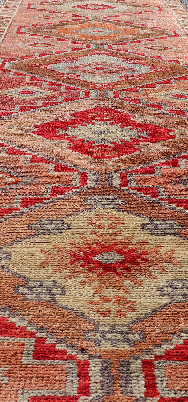 Measures: 2'10 x 11'10 Vintage Turkish Oushak Runner with Tribal Medallions in Redish Tones. Keivan Woven Arts / rug TU - NED - 4688, country of origin / type: Turkey / Oushak, circa 1950. This vintage Oushak runner features a unique blend of cheerfu... - Keivan Woven ArtsTU - NED - 4688 - 22111Rug
