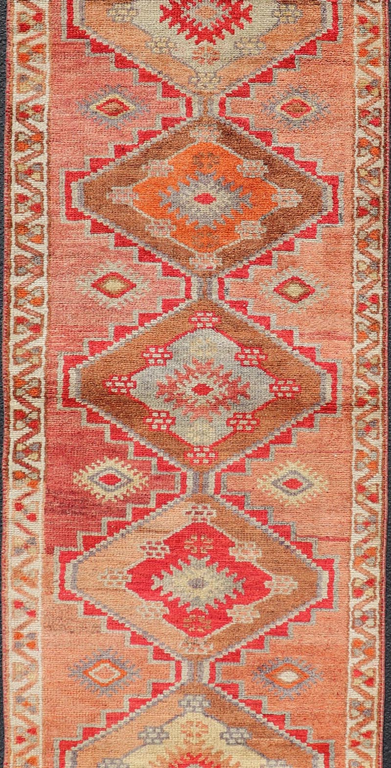 Measures: 2'10 x 11'10 Vintage Turkish Oushak Runner with Tribal Medallions in Redish Tones. Keivan Woven Arts / rug TU - NED - 4688, country of origin / type: Turkey / Oushak, circa 1950. This vintage Oushak runner features a unique blend of cheerfu... - Keivan Woven ArtsTU - NED - 4688 - 22111Rug