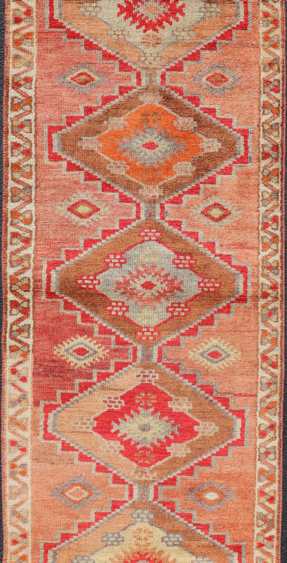Measures: 2'10 x 11'10 Vintage Turkish Oushak Runner with Tribal Medallions in Redish Tones. Keivan Woven Arts / rug TU - NED - 4688, country of origin / type: Turkey / Oushak, circa 1950. This vintage Oushak runner features a unique blend of cheerfu... - Keivan Woven ArtsTU - NED - 4688 - 22111Rug
