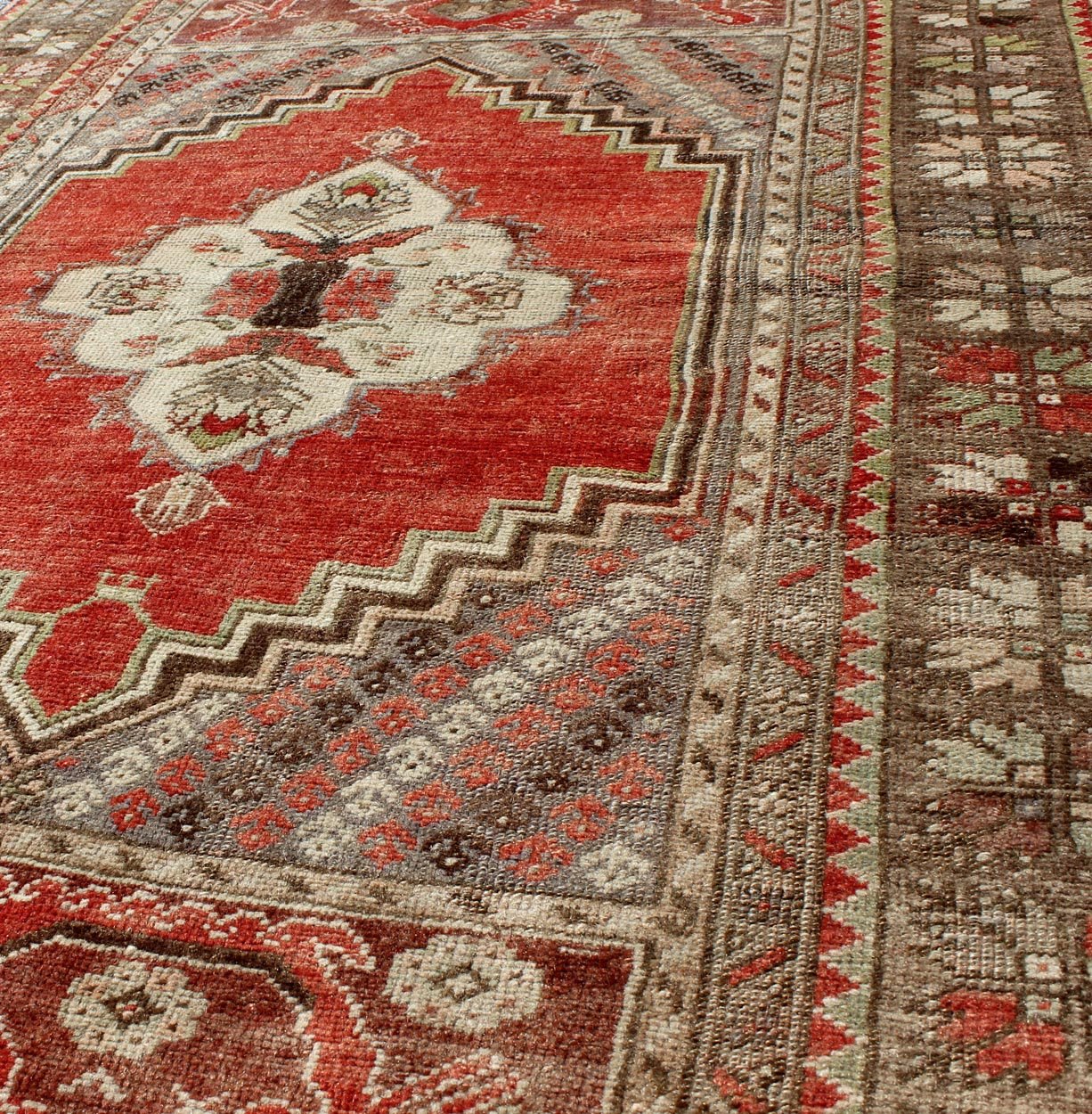 This antique Oushak bears a stylized medallion that commands the center field. A broad border of repeating motifs and floral patterns enclose the entire rug. Coral and light green colors complement the light brown, sub - geometric border. Turkish... - Keivan Woven ArtsTU - TRS - 136037 - 5048Rug
