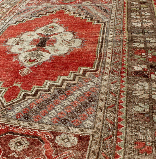 This antique Oushak bears a stylized medallion that commands the center field. A broad border of repeating motifs and floral patterns enclose the entire rug. Coral and light green colors complement the light brown, sub - geometric border. Turkish... - Keivan Woven ArtsTU - TRS - 136037 - 5048Rug