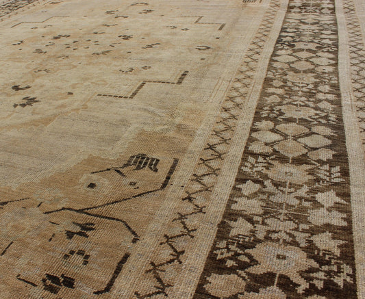 Vintage Turkish Floral Medallion Oushak Area Rug in Tan, Brown and Beige Measures: 7'11 x 11'5 This Vintage Turkish Oushak, from 1940s Turkey, featuring a chocolate brown border with connecting flower and vines. The sandy field combines ... - Keivan Woven ArtsTU - UGU - 14 - 3100Rug