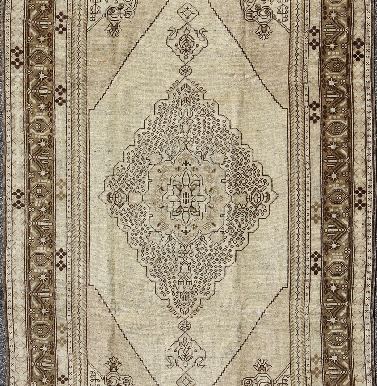 Vintage Turkish Stylized Medallion Oushak Rug in Sandy Neutrals and Earth Tones Measures: 5'7 x 10'2 This vintage Turkish Oushak sets on a neutral sandy ground with a central medallion stylized with small details. The background is ... - Keivan Woven ArtsTU - UGU - 56 - 2854Rug